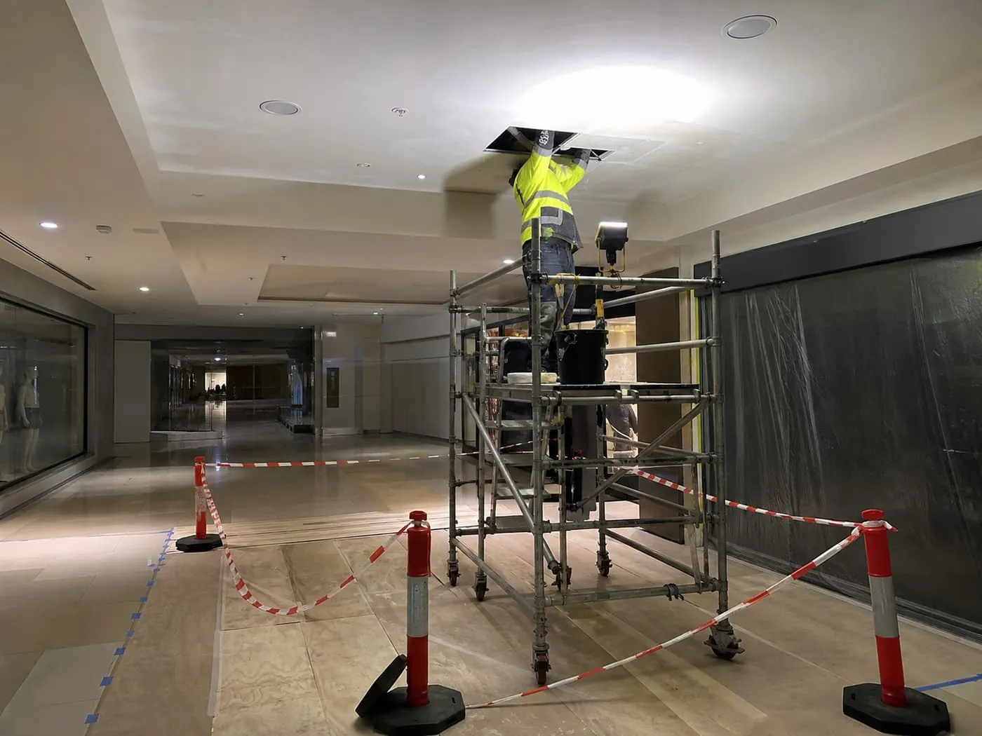 Ceiling repair and repainting in progress above a mall walkway.