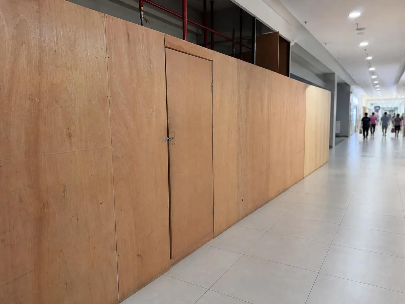Hoarding boards enclosing a work area in a mall corridor during operating hours.