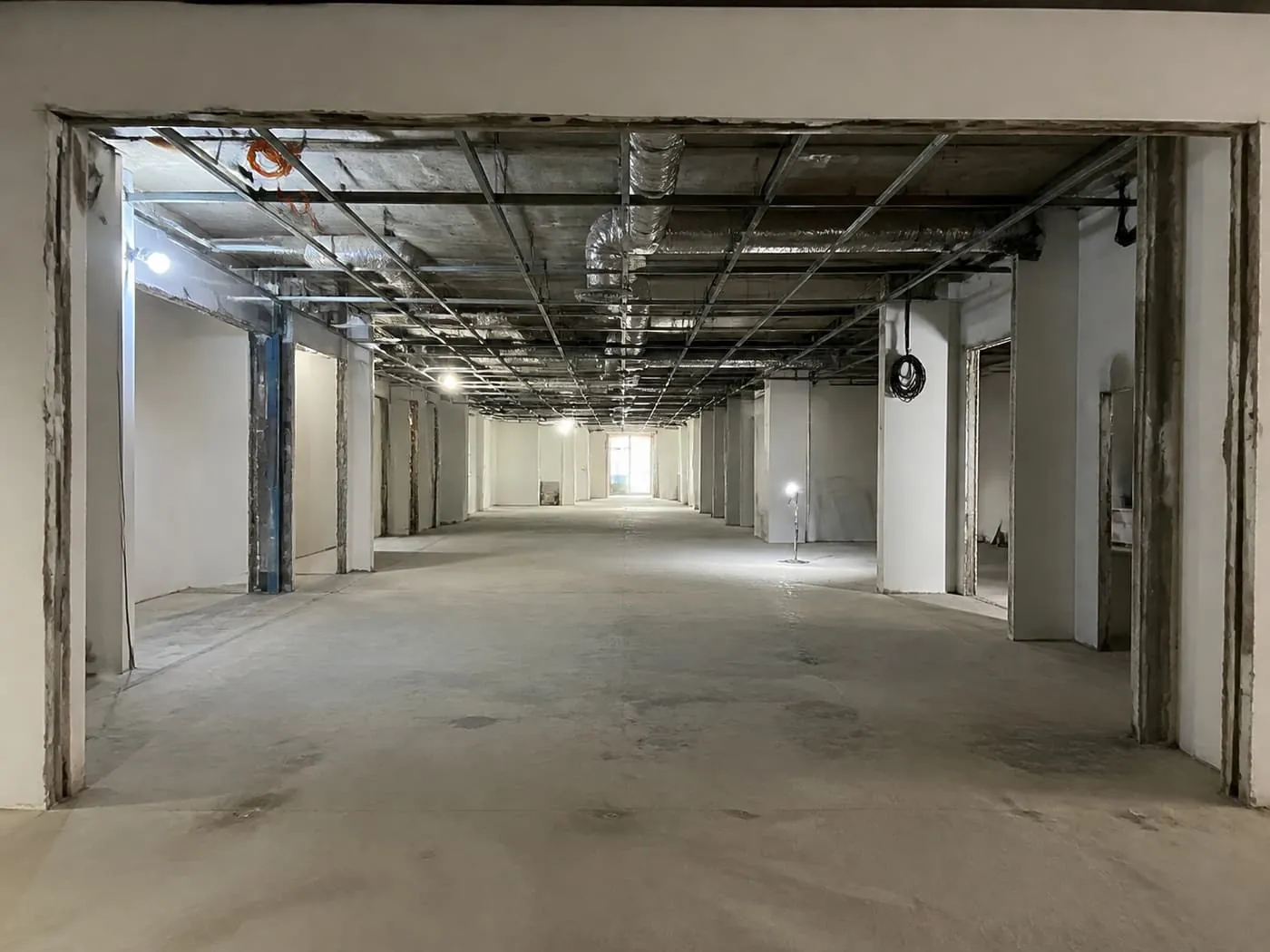 A retail lot stripped back to bare condition, ceiling grid and services exposed.
