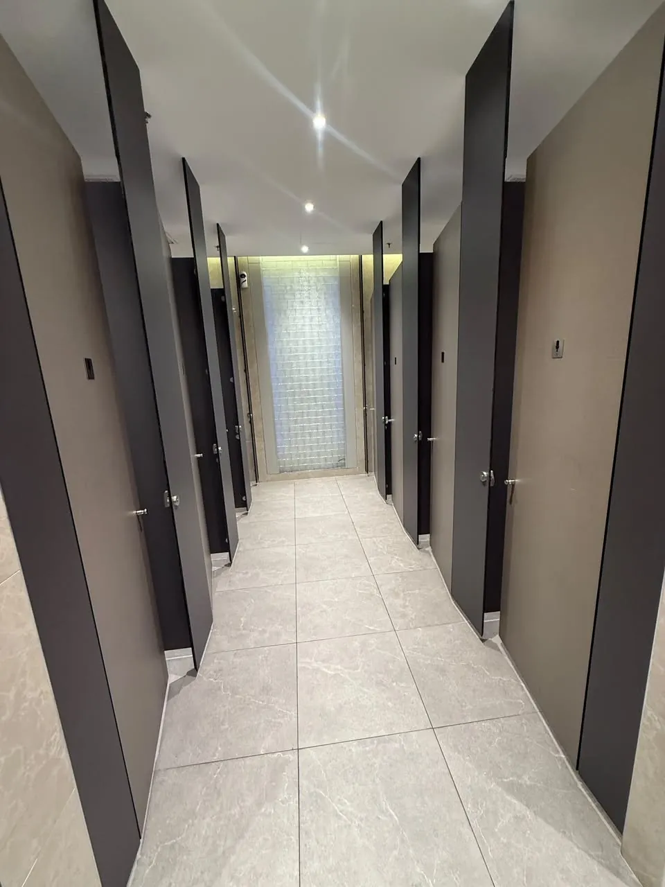 Completed cubicle corridor with new partitions, tiling and lighting in the upgraded mall toilet.