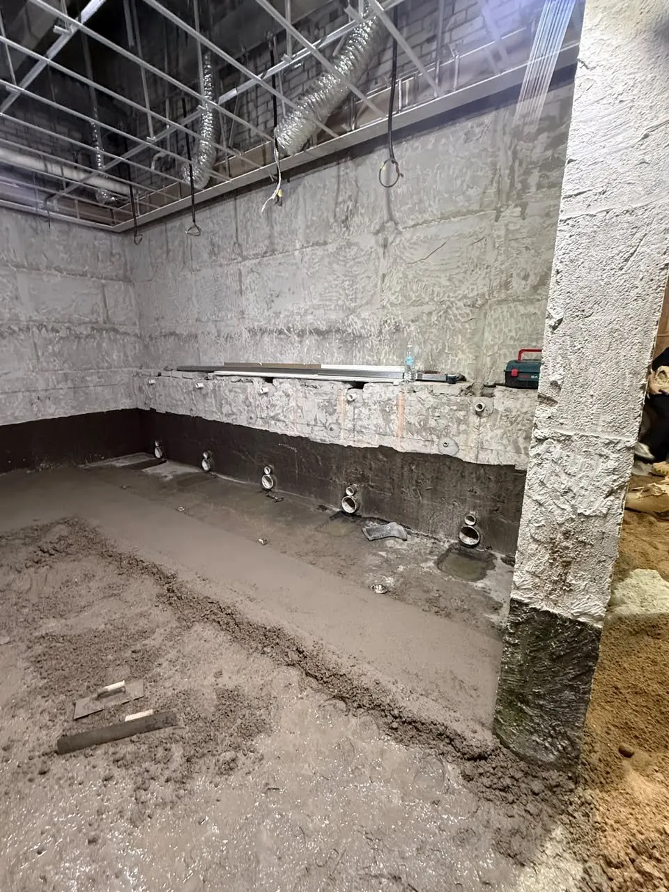 Public toilet stripped to the bare structural shell during upgrade works, with scaffolding overhead.