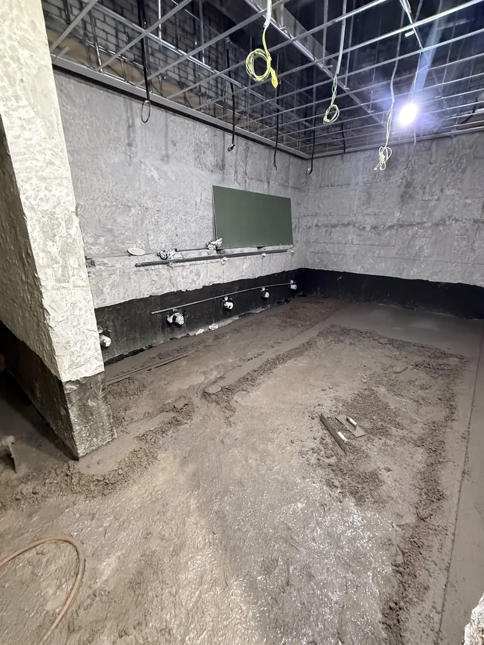 Waterproofing and floor screed stage of the toilet upgrade, services set out on the bare walls.